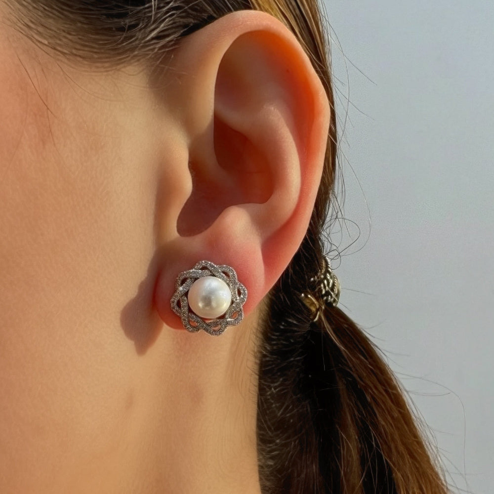 Close-up of a person wearing a pearl earring with a neutral background