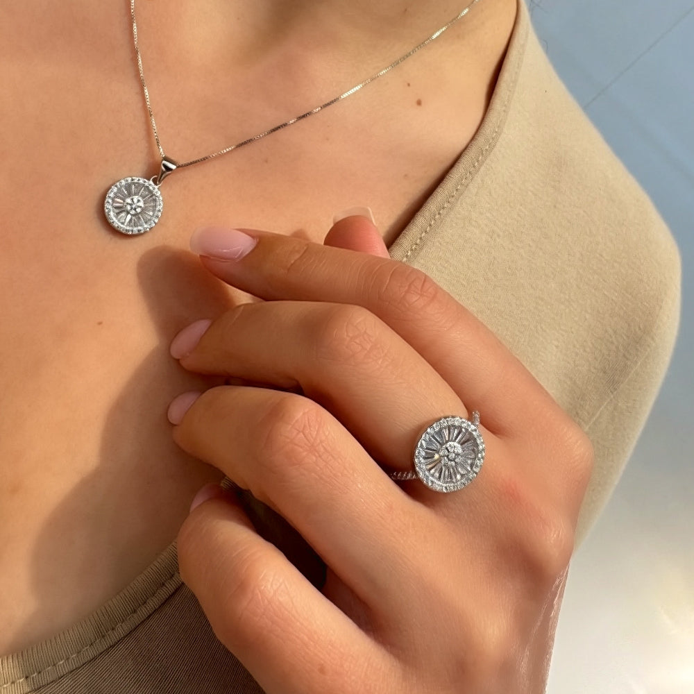 Close-up of a person wearing a silver necklace and ring with a blue background