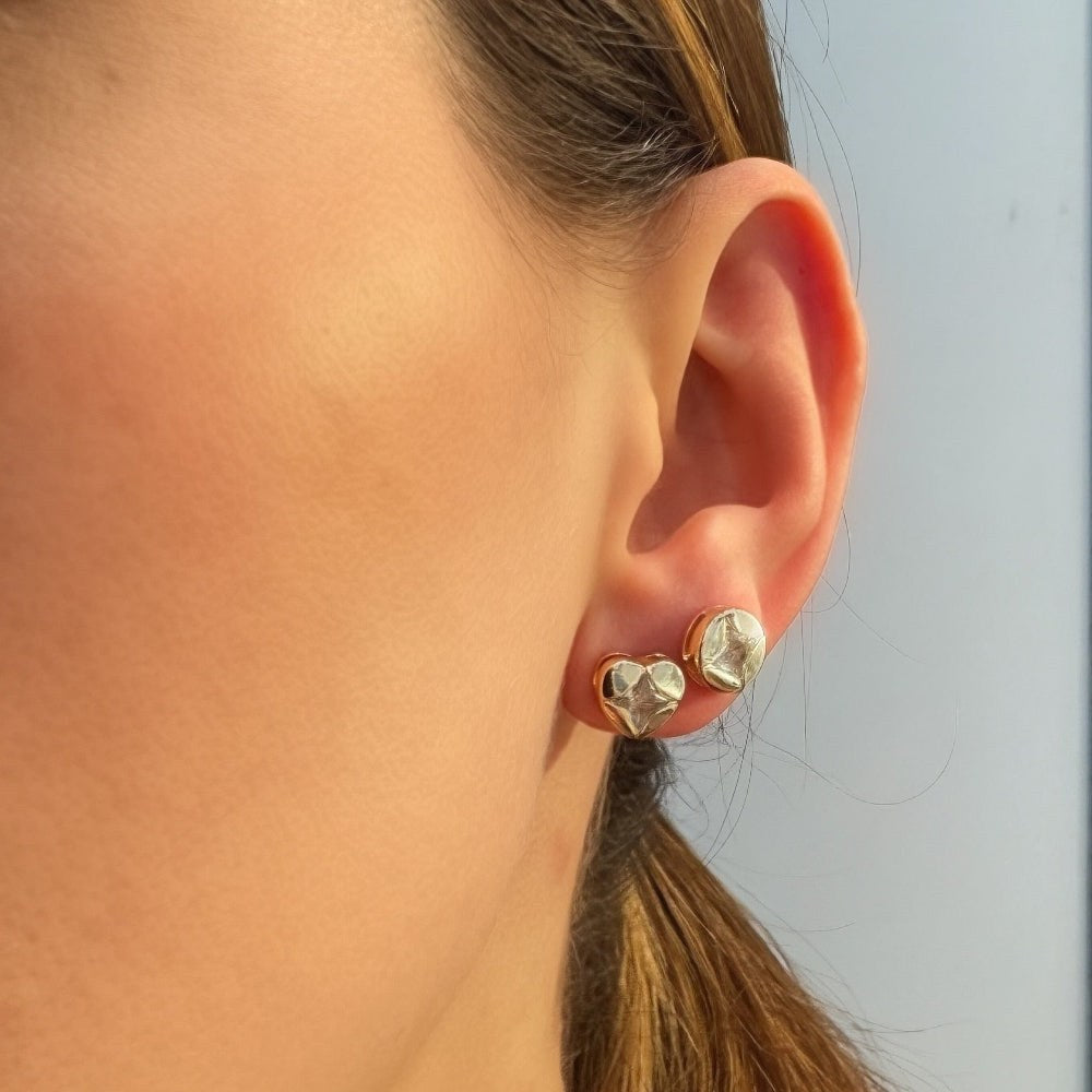 Close-up of a person wearing earrings with a blurred background of jewelry display.