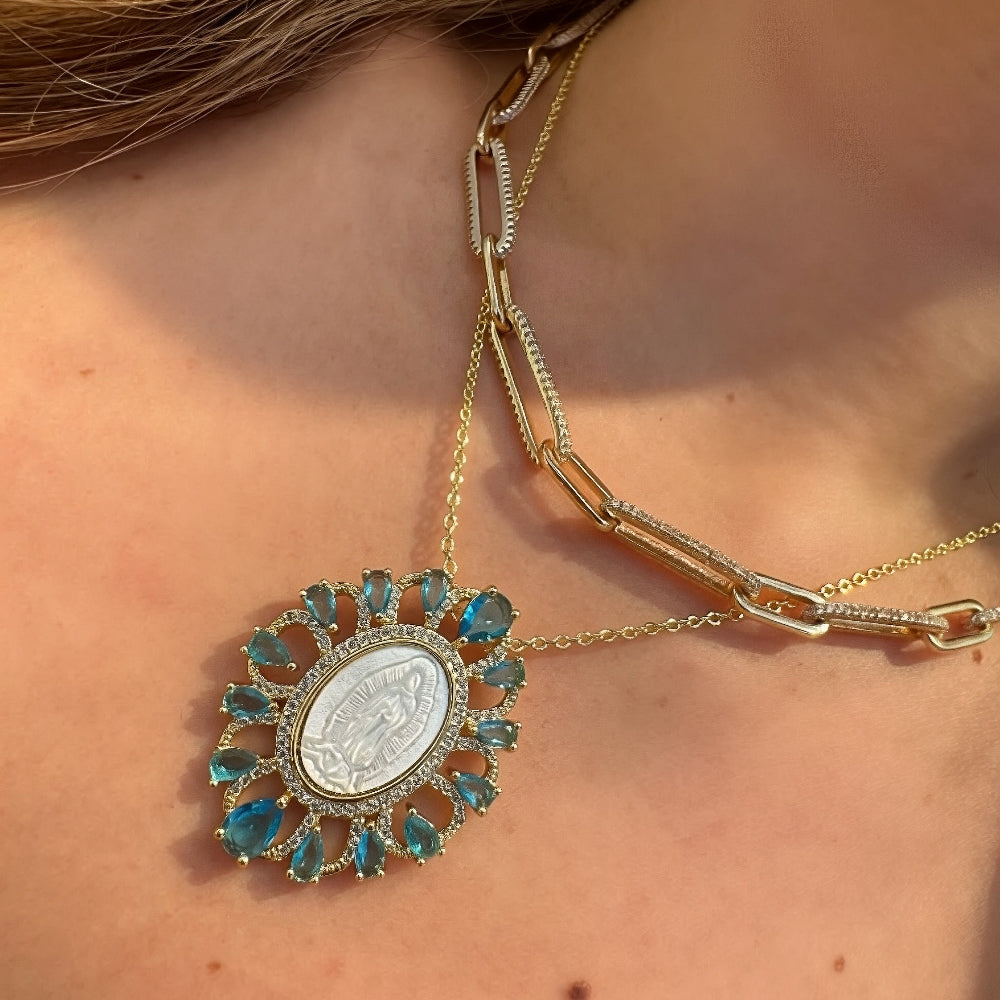 Close-up of a gold necklace with a decorative pendant on a person's neck.