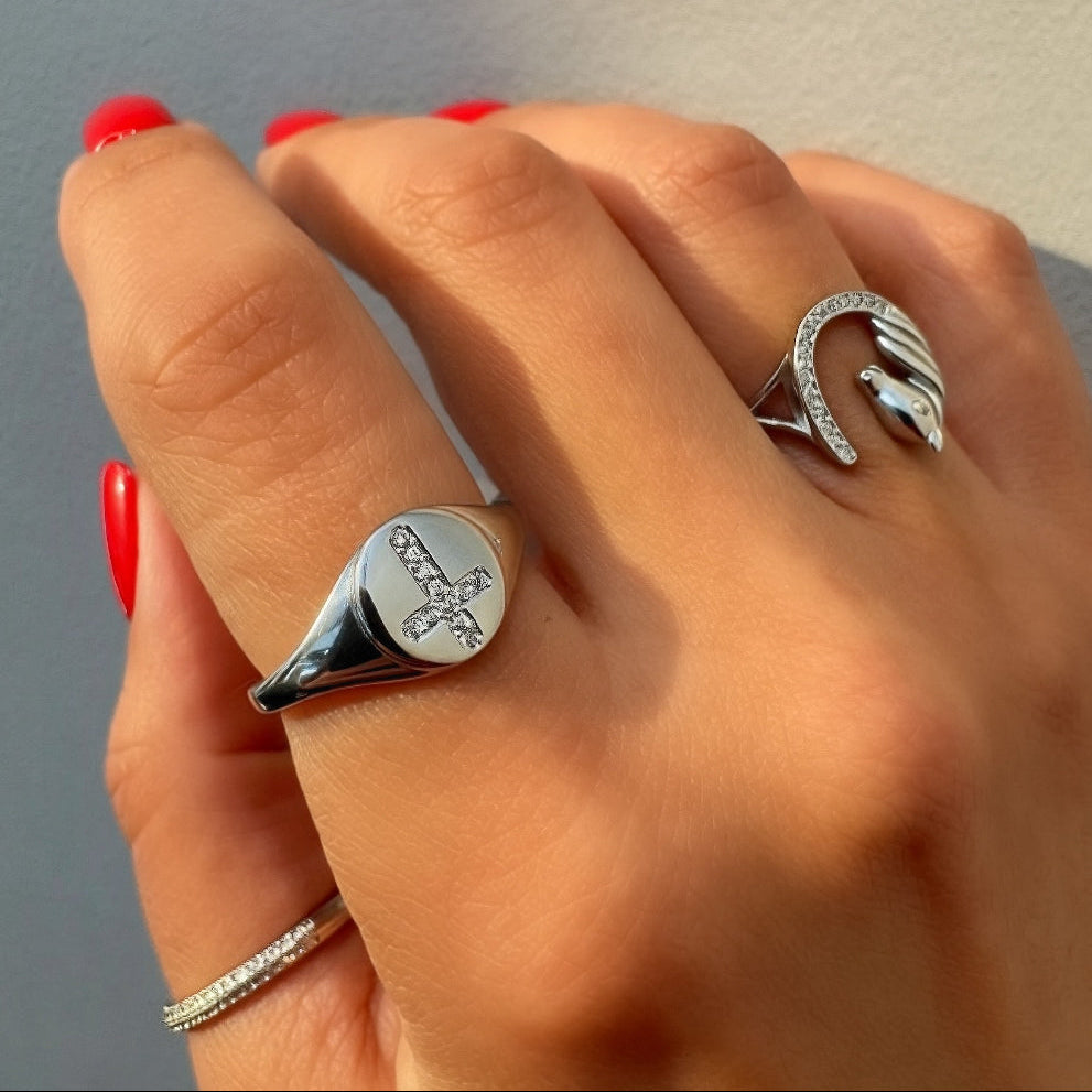 Hand wearing multiple silver rings with a plain background
