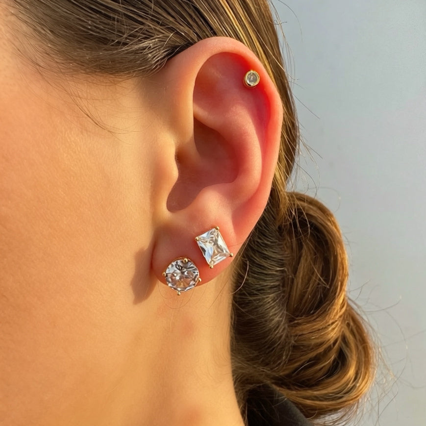Close-up of an ear wearing two diamond earrings with a blurred background