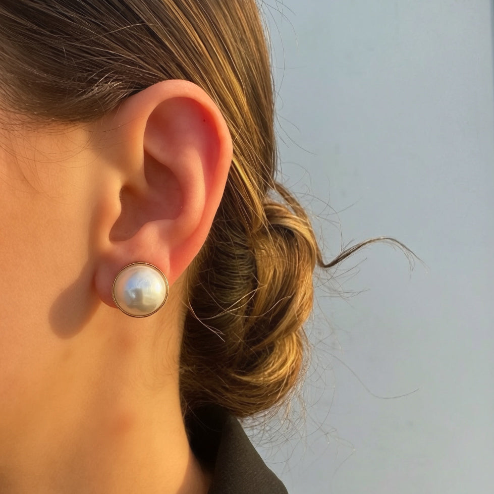 Close-up of an ear wearing a pearl earring with a blurred background