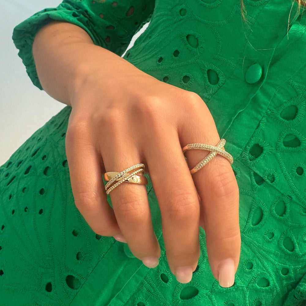 Hand wearing two gold rings on a green textured background