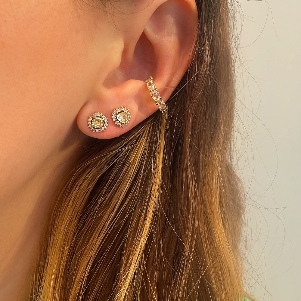 Close-up of an ear wearing gold hoop earrings with a neutral background