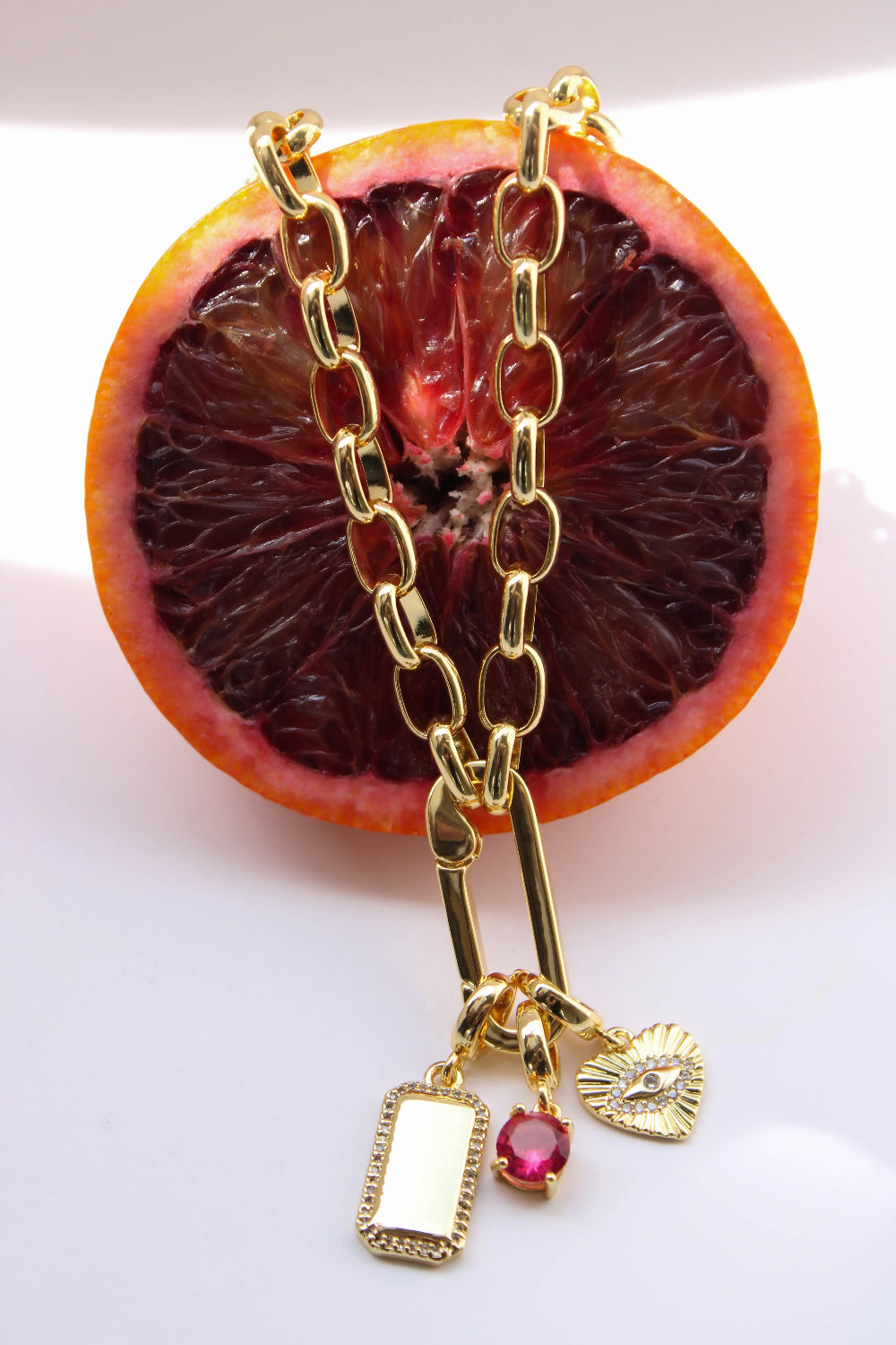 Gold chain necklace with charms on a halved blood orange