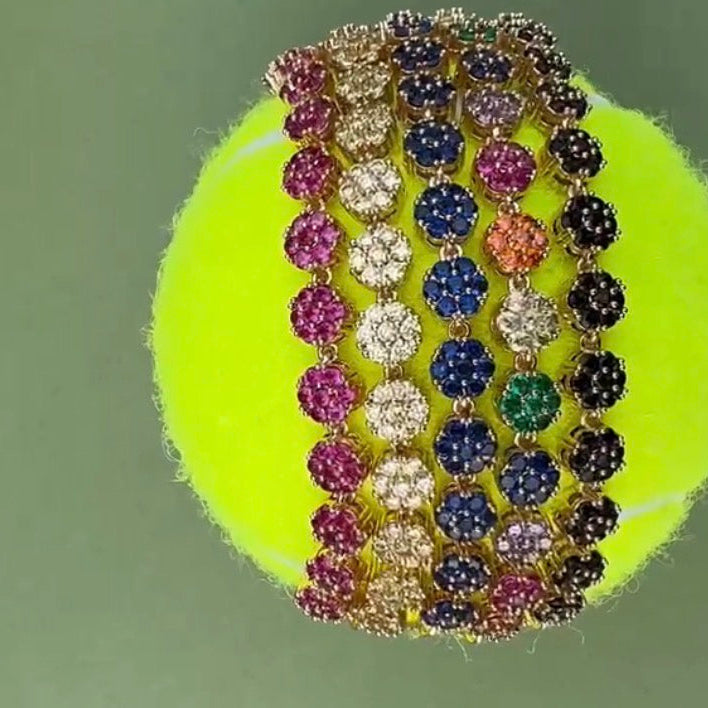 Multicolored gemstone bracelet on a tennis ball with a green background