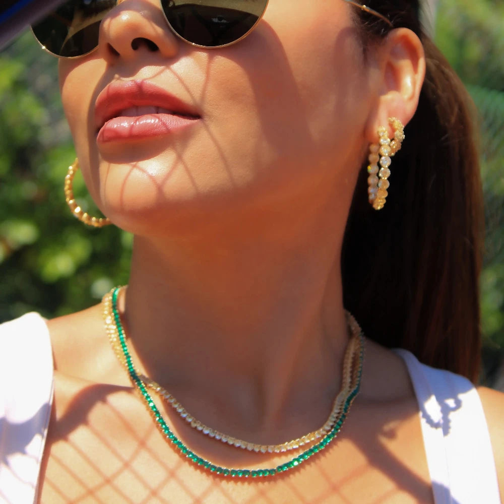 Woman wearing sunglasses and pearl earrings with a blurred background
