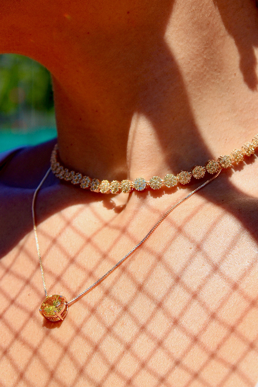 Close-up of a person wearing a delicate necklace with a pendant on a blurred natural background