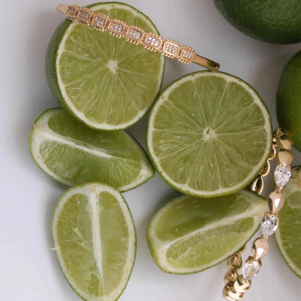 Jewelry set with gold chain and diamond accents displayed on sliced limes.
