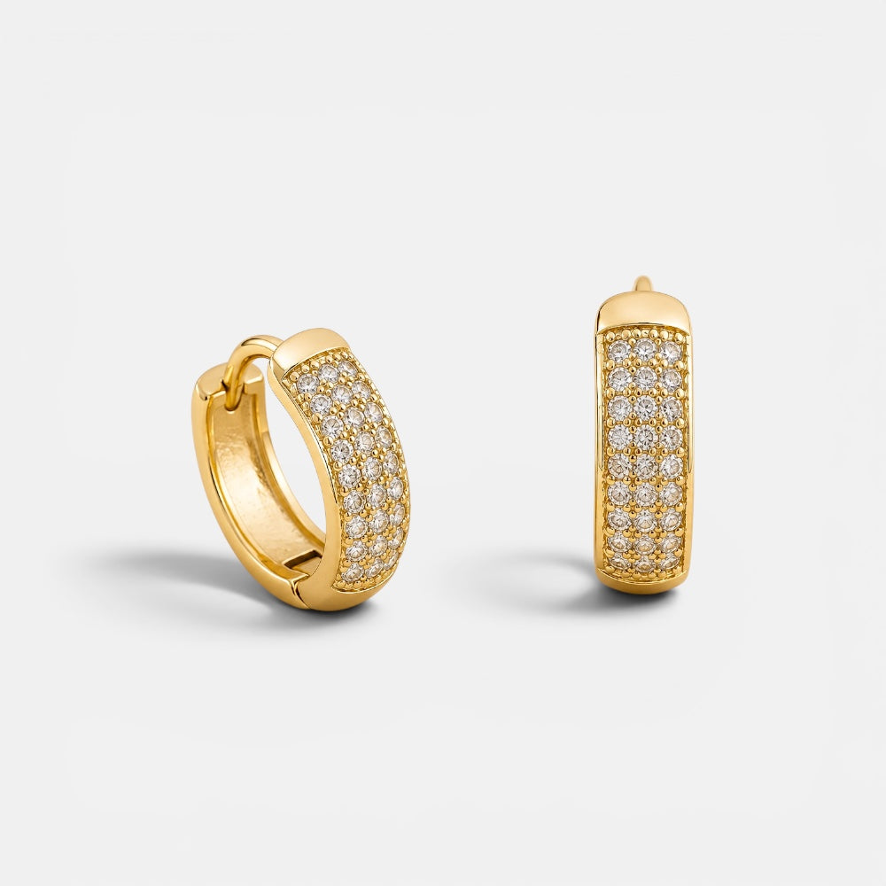 Gold hoop earrings with embedded diamonds on a light gray background