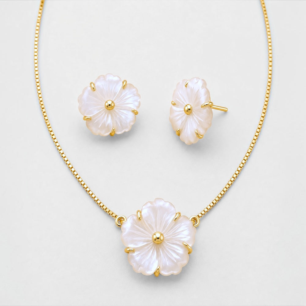 A gold jewelry set featuring a necklace and matching stud earrings with flower-shaped pendants made of iridescent white mother-of-pearl, displayed on a light gray background.