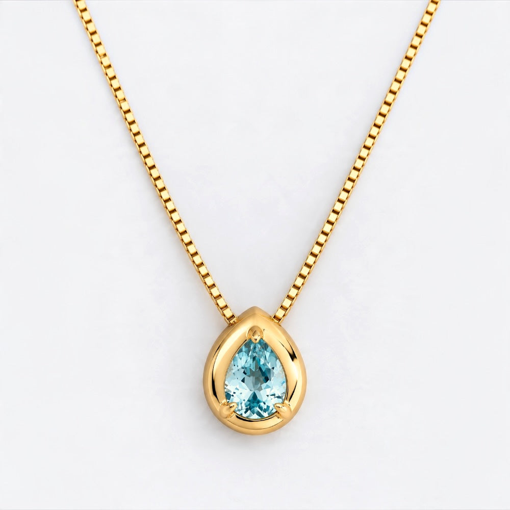 A gold teardrop pendant necklace featuring a light blue teardrop-cut gemstone, suspended from a delicate gold box chain against a clean white background.