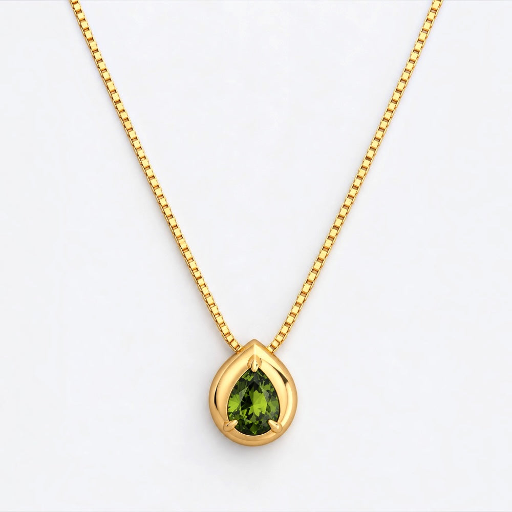 A gold chain necklace with a teardrop-shaped pendant featuring a green gemstone, set against a plain white background.