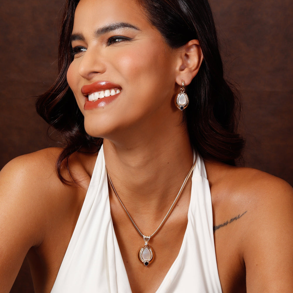 Woman wearing a white halter top with jewelry against a brown background