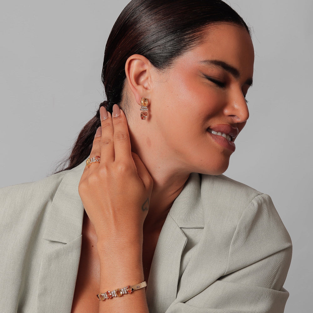 Woman wearing earrings and a bracelet against a neutral background