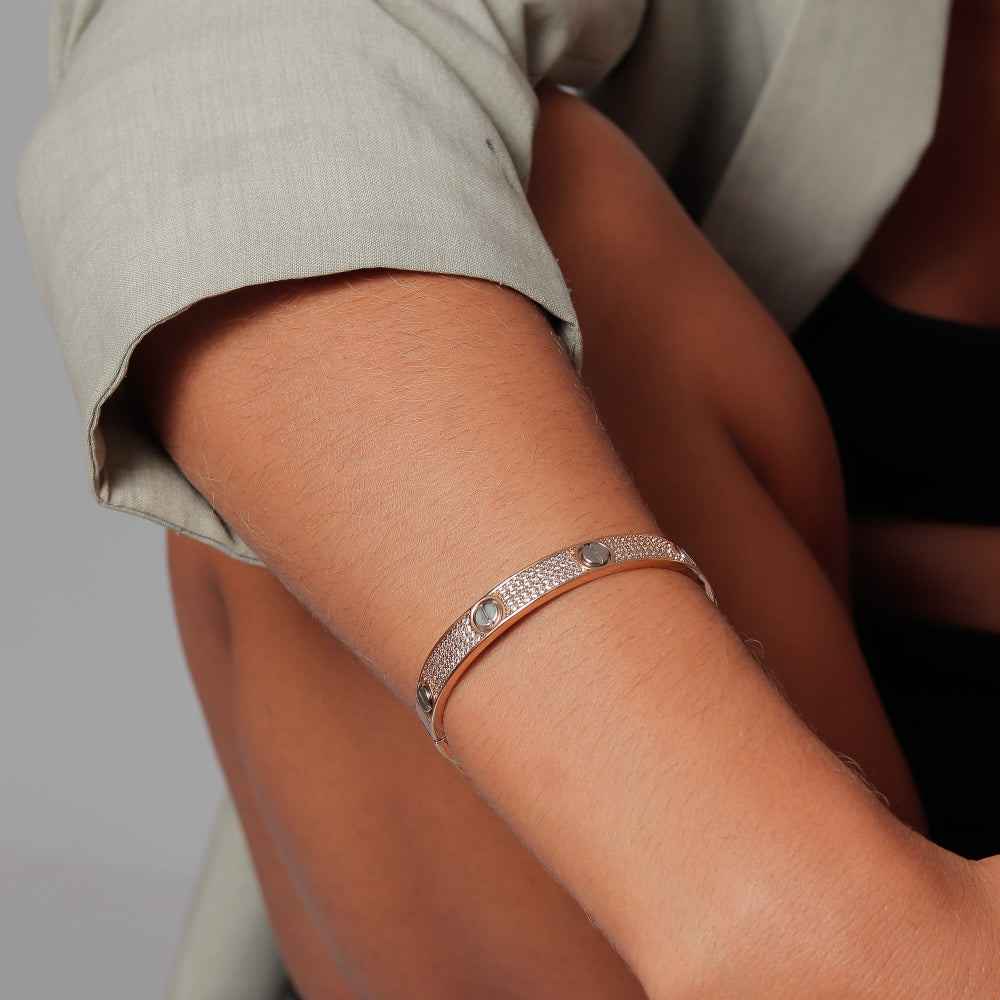Close-up of a person's arm wearing a silver bracelet on a neutral background