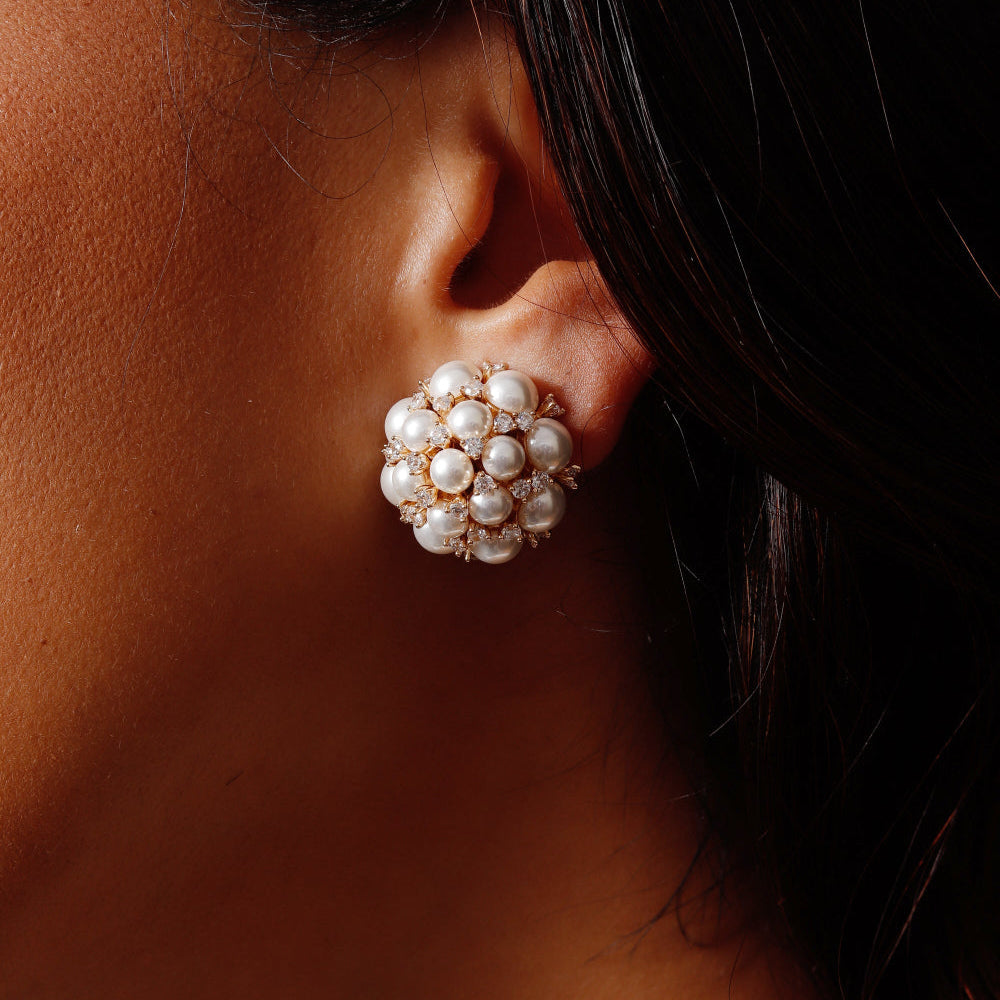 Close-up of an ear wearing a pearl earring with dark hair.