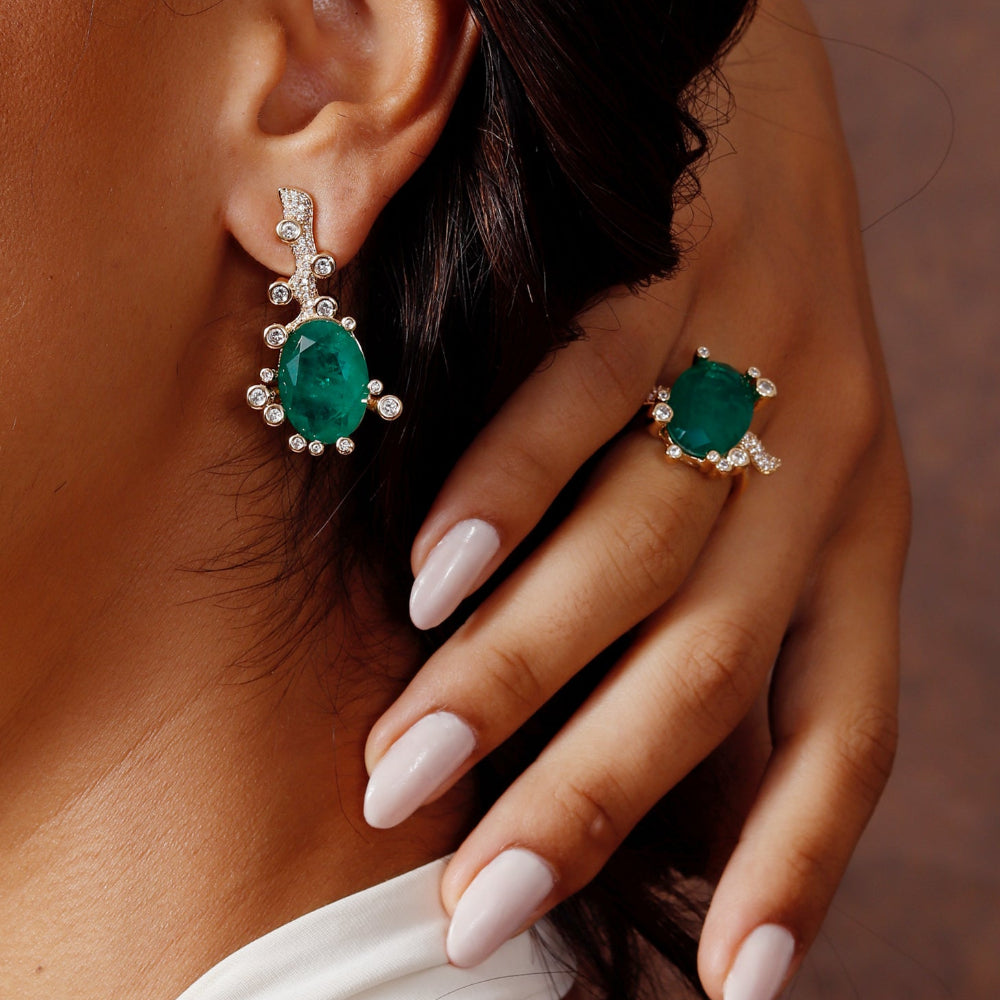 Close-up of a person wearing emerald green earrings and a ring
