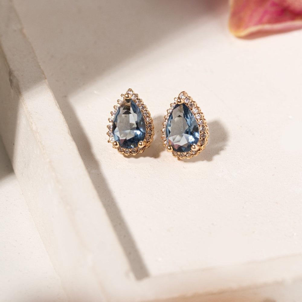 Gold-plated teardrop crystal stud earrings with aquamarine-blue centre crystals and clear crystal halos