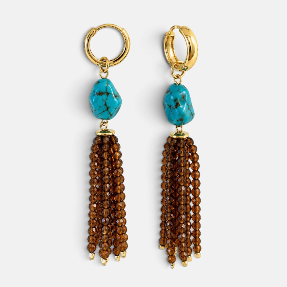 Close-up of gold-plated hoop earrings with reconstituted turquoise and long faceted brown jade bead tassels