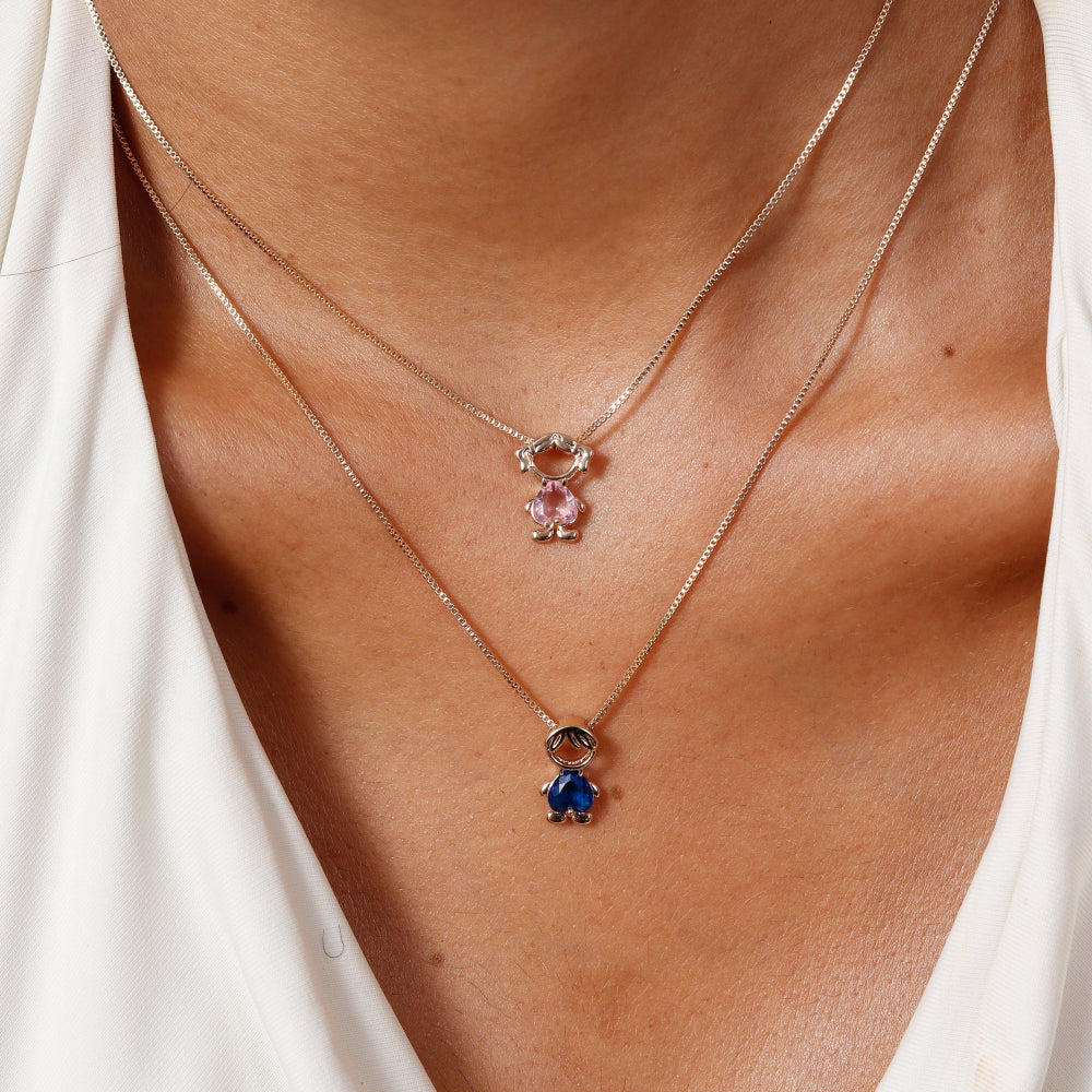 Necklace with pink and blue gemstones worn by a person in a white top.